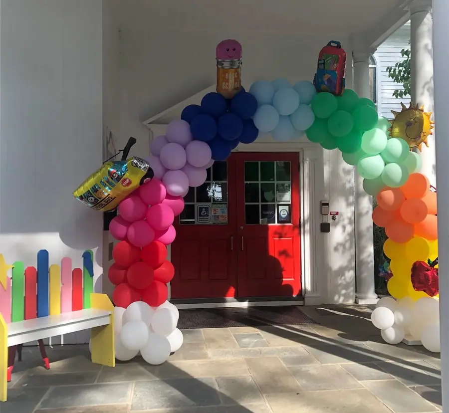 A colorful balloon arch is in front of the entrance to a house.