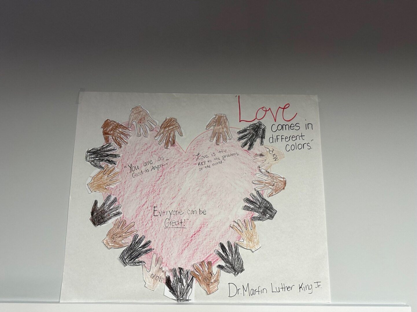 A heart shaped poster with hands and the word love written on it.